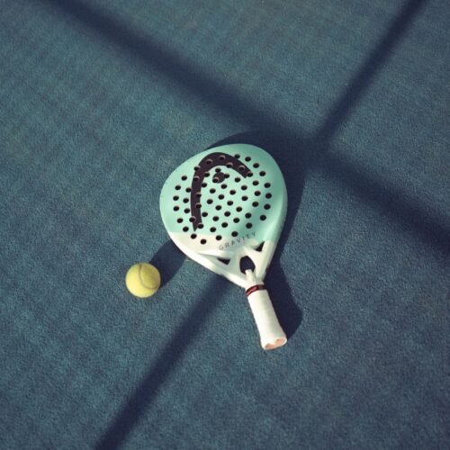 Raquette de padel et balle au soleil sur un court
